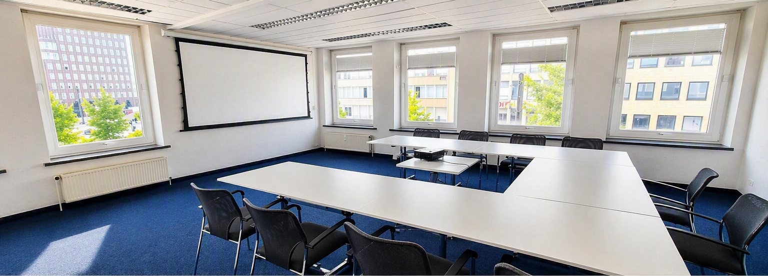 Seminarraum München: U-Tisch mit Beamer, Leinwand und großen Fenstern